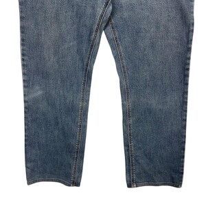 K&ouml;nnte beinhalten: Nahaufnahme einer blauen Jeans. Die Jeans hat ein klassisches F&uuml;nf-Taschen-Design mit sichtbaren N&auml;hten und einer verwaschenen Optik. Die Beine sind gerade geschnitten, und der Stoff scheint ein mittelschwerer Denim zu sein.