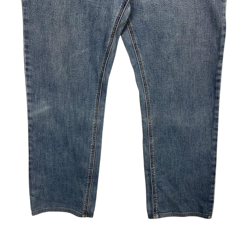 K&ouml;nnte beinhalten: Nahaufnahme einer blauen Jeans. Die Jeans hat ein klassisches F&uuml;nf-Taschen-Design mit sichtbaren N&auml;hten und einer verwaschenen Optik. Die Beine sind gerade geschnitten, und der Stoff scheint ein mittelschwerer Denim zu sein.