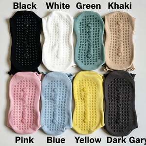 May include: Eight pairs of yoga socks arranged in two rows, featuring colors black, white, green, khaki, pink, blue, yellow, and dark gray. Each sock has a textured grip pattern on the sole with the text Yoga Socks printed in the center.
