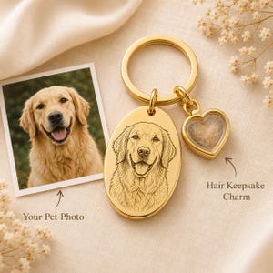 May include: A gold-colored keychain with an oval pendant featuring a detailed engraved portrait of a Golden Retriever. A heart-shaped charm holds pet hair. A photo of the dog is next to the keychain. Text reads "Your Pet Photo" and "Hair Keepsake Charm."