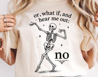 May include: A cream-colored short-sleeve t-shirt featuring a black graphic of a dancing skeleton. Above the skeleton, the text reads, "or, what if, and hear me out:" and below the skeleton, the word "no" is printed in a bold, serif font.