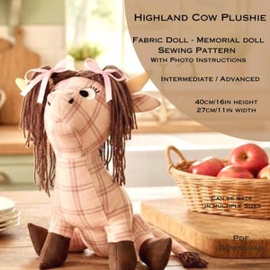 May include: A Highland cow plushie made from fabric, with a plaid pattern in shades of pink and brown. The plushie has brown fringe hair, small horns, and is 16 inches tall and 11 inches wide. The image also includes text about a sewing pattern.