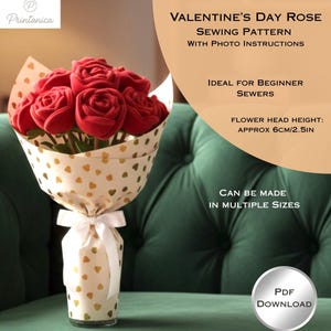 Può includere: Un bouquet di rose rosse in tessuto avvolto in carta dorata a forma di cuore, legato con un nastro bianco. L'immagine include il testo: "Valentine's Day Rose Sewing Pattern" e "Altezza capolino: circa 6cm".