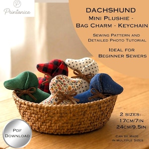 May include: A collection of five fabric dachshund plushies in a woven basket, featuring green, red plaid, floral, white with black dots, and blue denim patterns. Each plushie has a brown ribbon bow. Text includes DACHSHUND MINI PLUSHIE and 2 SIZES: 17CM/7IN 24CM/9.5IN.