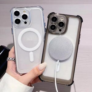 May include: Two clear phone cases with protective bumpers. One case has a white magnetic charging ring and a white charging port. The other case has a silver magnetic charging ring and a white charging port.