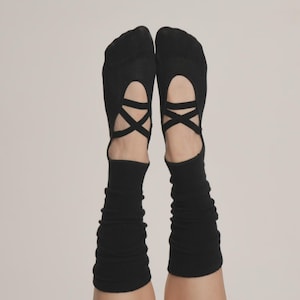 Puede incluir: Calcetines negros estilo ballet con correas entrecruzadas en la parte superior del pie. Los calcetines tienen un dise&ntilde;o recortado y se extienden hasta la parte inferior de la pierna. El fondo es de color neutro s&oacute;lido.
