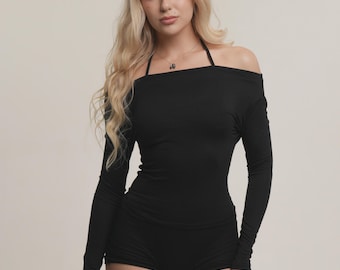 May include: A black off-the-shoulder long-sleeve top and matching shorts. The top has a halter neck and long sleeves. The shorts are high-waisted and form-fitting. The outfit is made of a soft, stretchy material.