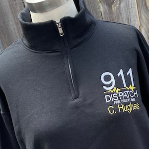May include: Black 1/4 zip sweatshirt with a white and yellow embroidered design that says "911 Dispatch Fire Police EMS C. Hughes"