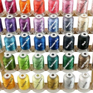 May include: A collection of colorful thread spools, each labeled with a different color name. The spools are arranged in rows, showcasing a wide range of hues, including red, blue, green, and yellow. Ideal for sewing and embroidery projects.