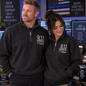 May include: A black quarter-zip sweatshirt featuring white and yellow embroidered text that reads 911 DISPATCH FIRE POLICE EMS and the name C. Hughes. The design includes a yellow heartbeat line graphic above the name on the left chest area.
