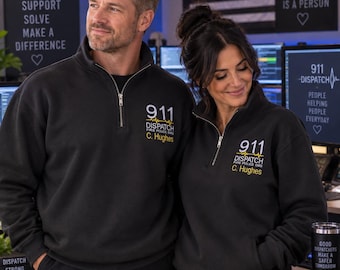 May include: A black quarter-zip sweatshirt featuring white and yellow embroidered text that reads 911 DISPATCH FIRE POLICE EMS and the name C. Hughes. The design includes a yellow heartbeat line graphic above the name on the left chest area.
