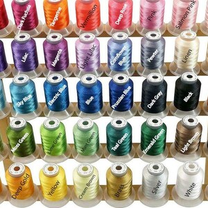 May include: A wooden spool rack with 48 spools of thread in various colors, including red, purple, orange, green, blue, pink, brown, beige, black, white, and gray. The spools are arranged in rows and columns on the rack.