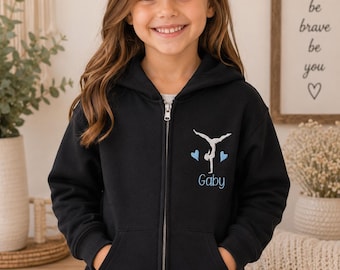 May include: Black zip-up hoodie with a gymnast design and the name "Gaby" in blue. The design includes a gymnast silhouette and two blue hearts. The hoodie has a full zipper and front pockets.