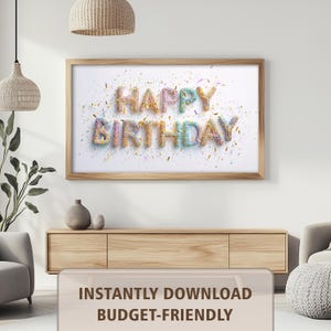 May include: A framed print with the words "HAPPY BIRTHDAY" in colorful, textured letters. The letters are surrounded by confetti on a white background. The frame is made of light-colored wood. The image is hanging on a white wall.