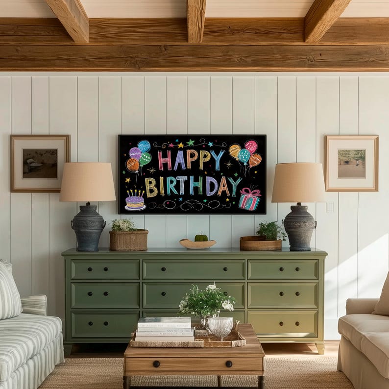 May include: A living room scene featuring a green dresser with nine drawers, two lamps, and a coffee table. A black sign on the wall displays the words "HAPPY BIRTHDAY" with colorful balloons and a gift box. Two framed pictures are on the wall.