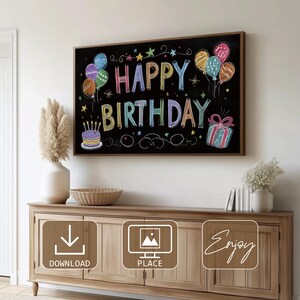 May include: A framed chalkboard with the words "HAPPY BIRTHDAY" in colorful chalk lettering. The design includes balloons, stars, a cake with candles, and a wrapped gift. The chalkboard is displayed above a wooden cabinet.