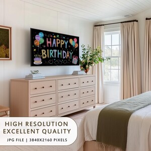 May include: A bedroom scene with a large TV displaying "Happy Birthday" in colorful chalk-style lettering. The TV is mounted above a light wood dresser with multiple drawers. The room has neutral tones, with beige curtains and a white bedspread.