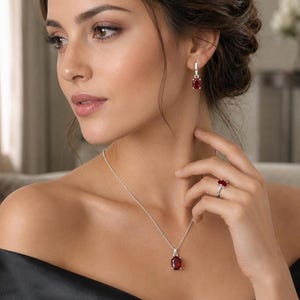Può includere: Un set di gioielli composto da una collana in argento con un ciondolo in pietra preziosa rosso scuro dal taglio ovale, orecchini pendenti abbinati con pietra rossa ovale e un anello in argento con una singola pietra rossa ovale su fascia.