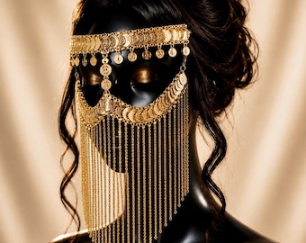 May include: A gold-toned metal face mask featuring a horizontal band of circular coin-like charms across the forehead and a scalloped section over the eyes, with long, delicate hanging chains that drape down to cover the lower face area.