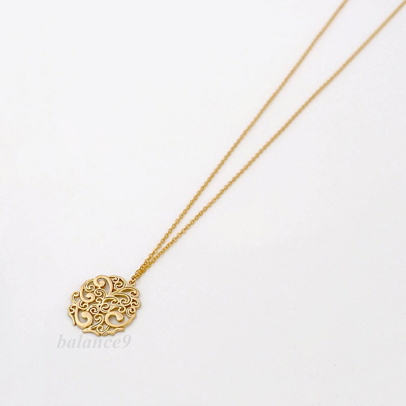 May include: A gold necklace with a delicate, circular pendant featuring a filigree design. The pendant is intricately detailed with swirling patterns.