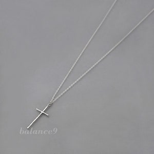 May include: A silver chain necklace with a simple cross pendant.
