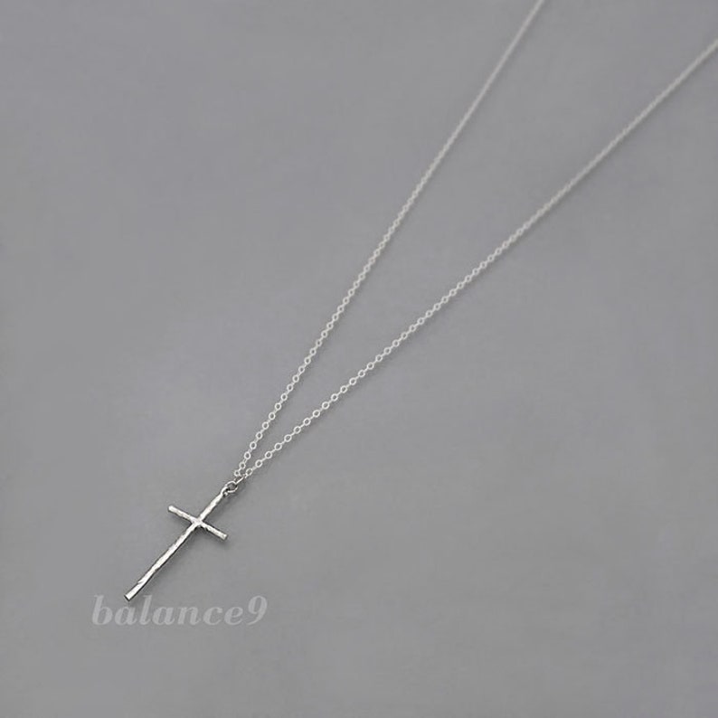 May include: A silver chain necklace with a simple cross pendant.