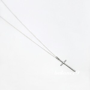 May include: A silver chain necklace with a simple silver cross pendant.