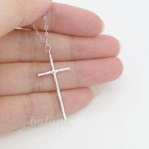 May include: A silver chain necklace with a textured silver cross pendant.