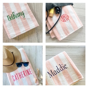 May include: A collection of four soft, plush towels featuring vertical stripes in white and light pink. Each towel is personalised with embroidered names or monograms in various colours, including green, pink, and dark purple thread.