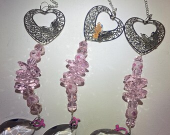 May include: Three silver heart-shaped wind chimes with pink crystal beads and a teardrop-shaped crystal at the bottom. Each heart features a butterfly design.