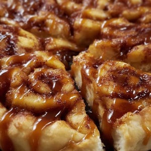 Peut inclure: Gros plan sur un roulé à la cannelle fraîchement cuit, coupé en sections. La pâtisserie est brun doré avec un tourbillon de cannelle et un généreux filet de sauce au caramel. L'image met en évidence les textures et les couleurs du dessert.