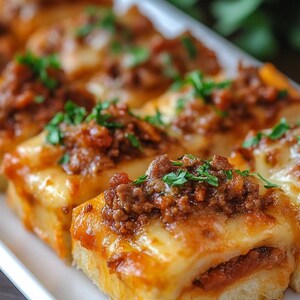 May include: A close-up shot of several small, rectangular appetizers on a white plate. Each piece features a base of bread, topped with a layer of melted cheese, a red sauce, and a sprinkle of chopped green herbs. The appetizers have a warm, inviting appearance.