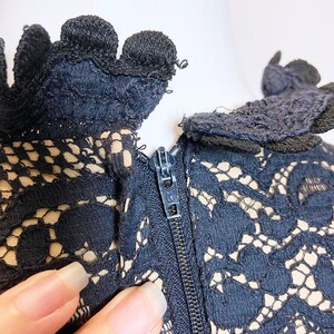 May include: Black lace dress with a zipper closure at the back. The lace has a delicate floral pattern.