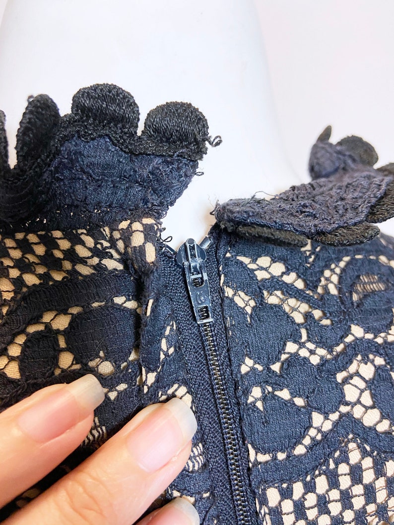 May include: Black lace dress with a zipper closure at the back. The lace has a delicate floral pattern.