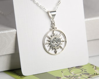 Puede incluir: Un collar de plata con un colgante de brújula. La brújula tiene un diseño de estrella de plata y las letras N, S, E y W están grabadas en la cara de la brújula.
