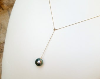 Puede incluir: Un collar de cadena de oro con un solo colgante de perla verde oscuro.