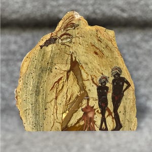 May include: A unique, hand-painted artwork on a stone slab. The artwork depicts stylized figures, animals, and fish in earthy tones of brown, beige, and black. The piece has a rough, natural texture and a distinctive shape.