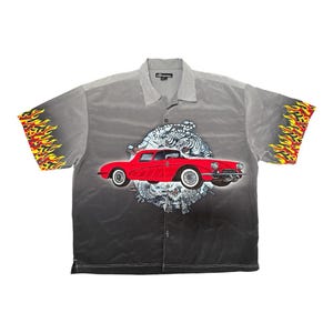 May include: A button-down shirt with a gradient gray design. The shirt features a red classic car graphic, a white tiger, and flames on the sleeves. The shirt has short sleeves and a collared neckline.