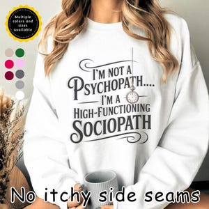 May include: White sweatshirt with the text "I'M NOT A PSYCHOPATH... I'M A HIGH-FUNCTIONING SOCIOPATH" in black. A small pocket watch graphic hangs from the text. The sweatshirt also features a selection of available colors and sizes.