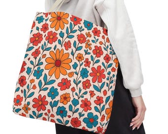 May include: A floral tote bag featuring a repeating pattern of orange, red, and blue flowers with green leaves on a cream background. The bag has a cream-colored strap and is carried over the shoulder.