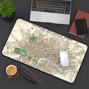 May include: A rectangular mouse pad featuring a vintage map of London, with the title "Whitbread's New Plan of London." The map is in shades of beige, green, and blue. A white computer mouse sits on the pad, with a laptop and other office supplies in the background.