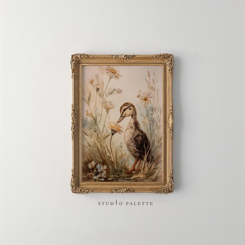 May include: A framed watercolor print of a duckling in a field of wildflowers. The duckling is brown and white with orange feet. The frame is gold with ornate detailing. The text "STUDIO PALETTE" is at the bottom.