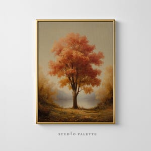 Puede incluir: Impresión artística enmarcada que presenta un árbol otoñal vibrante con hojas naranjas y amarillas. El árbol se alza en un campo con un lago al fondo. La obra de arte está en un marco dorado y tiene el texto "STUDIO PALETTE" en la parte inferior.