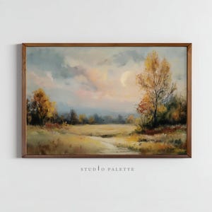 Peut inclure: Peinture à l'huile encadrée d'un paysage avec des arbres d'automne et un champ. Le ciel présente de doux tons roses et bleus, avec une pleine lune visible. La peinture est dans un cadre en bois marron. Le texte "STUDIO PALETTE" est en bas.