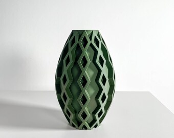 May include: A matte dark green vase with an oval silhouette, featuring a raised, repeating geometric diamond lattice pattern that wraps around the entire exterior surface, creating a textured, open-work grid effect.