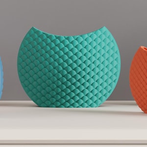 May include: Three decorative, textured vases in teal, orange, and blue. The vases have a rounded shape with a curved top. The surface of each vase is covered in a scale-like pattern. The vases are displayed on a white surface.