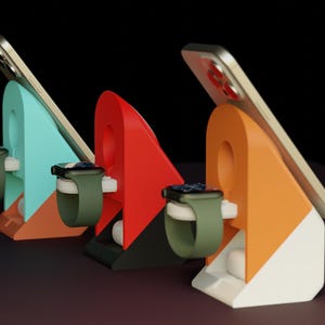 May include: Three angled charging stands in teal, red, and orange, each holding a smartphone and an olive green smartwatch. The stands feature a circular cutout and a white base section, providing a stable platform for devices to rest while charging.