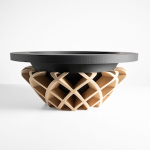 May include: A modern decorative bowl with a geometric design. The bowl features a black, circular top and a light brown, lattice-like base. The bowl is made of wood and is suitable for home decor.