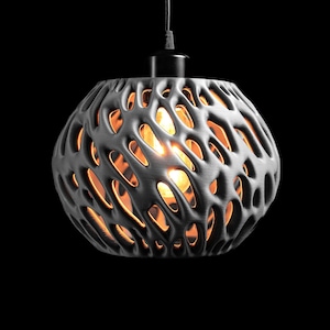 May include: A spherical pendant light fixture featuring a dark gray, organic, lattice-like outer shell with irregular, elongated cutouts. A warm, glowing light bulb is visible through the openings, suspended by a black cord and fixture.