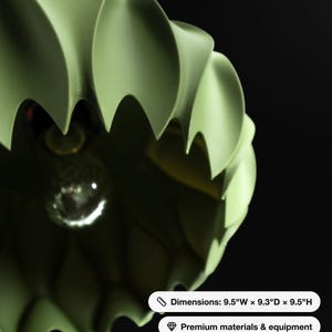 May include: A sage green pendant light fixture with a scalloped, ribbed exterior and a central light bulb. The fixture measures 9.5 inches wide, 9.3 inches deep, and 9.5 inches high, featuring a matte finish and a curved, petal-like design.